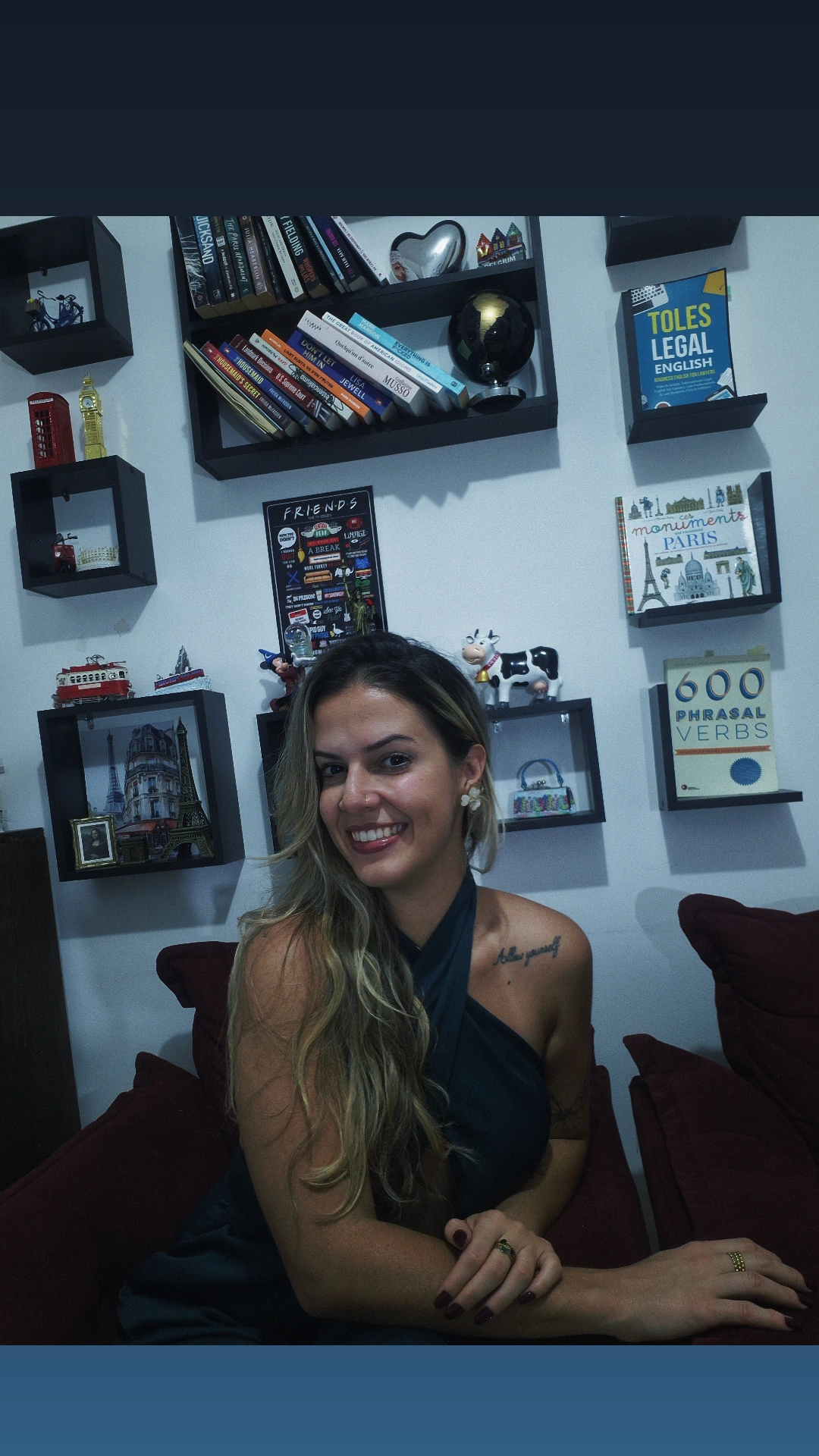 Isabela Almeida em frente à sua coleção de livros e lembranças de viagens